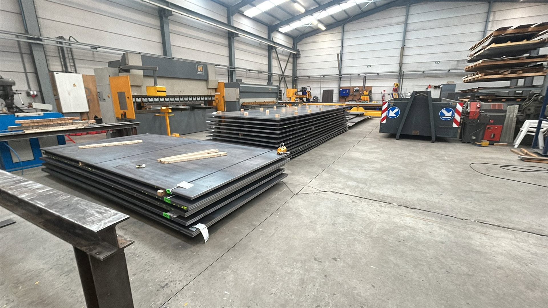 Werkplaats met stapels staalplaat, plaatschaar en kantbank